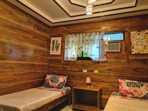 a room with wooden walls and two beds and a window at LADY GHAGHA ROOM RENTALs in San Vicente