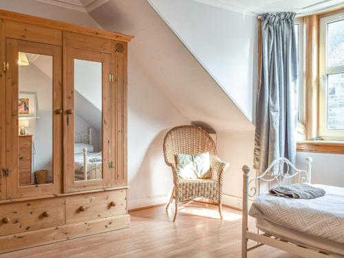 a bedroom with a bed and a dresser and a chair at Maisie Cottage in Saint Monance