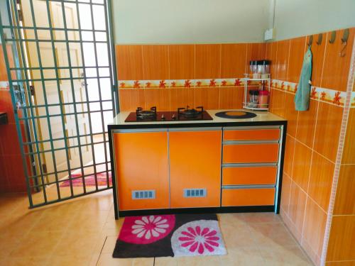 Il comprend une cuisine équipée d'un comptoir orange et d'une cuisinière. dans l'établissement D'LAILA HOMESTAY, 