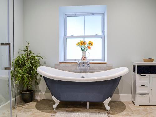Pearsie的住宿－Cullew Bothy，浴室设有蓝色和白色的浴缸,并带有窗户。