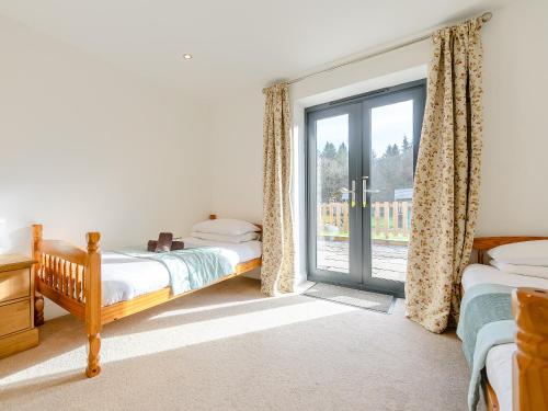 a bedroom with two beds and a sliding glass door at The Lodge in Upton Bishop