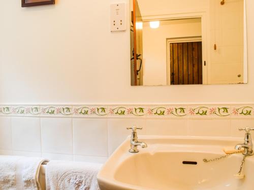 a bathroom with a sink and a mirror at The Hill Cottage Apartment in Wollaston