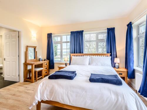 a bedroom with a large bed with blue curtains at White Oak Cottage in Ashby