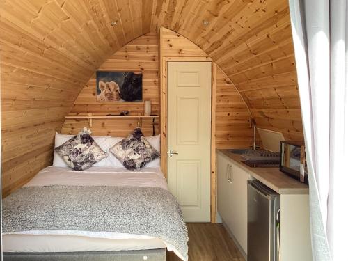 een slaapkamer in een tiny house met een bed bij The Dalmore Pod in Alness
