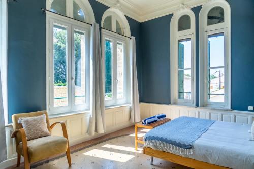 ペズナにあるUltimate Relaxation for Family or Group at Renowned Couvent des Ursulines, a Tranquil Escape in Historic Pézenasの青い壁のベッドルーム1室、ベッド1台、椅子1脚が備わります。