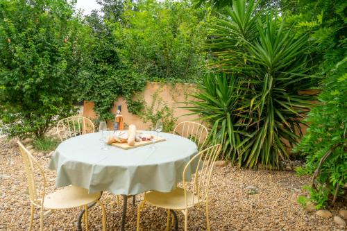 a white table with chairs and a bottle of wine at 5 Family Apartments with Pool & Large Garden in Historic Pézenas Convent in Pézenas