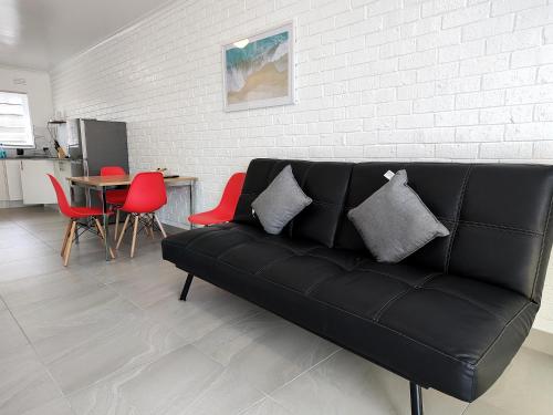 a black couch in a living room with red chairs at PROMO! Near Train Station, FREE WIFI! in Melbourne