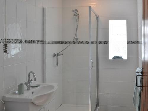 a white bathroom with a shower and a sink at The Butts Cottage in Stanhope