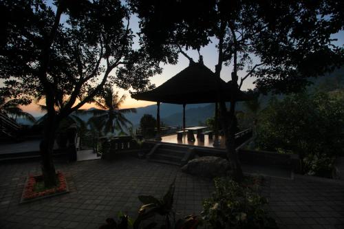 a patio with a tent and chairs and trees at Rostika Hotel Sekumpul in Buleleng