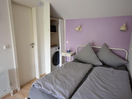 a bed in a bedroom with a purple wall at Beautiful holiday home in the middle of nature in Berlingen