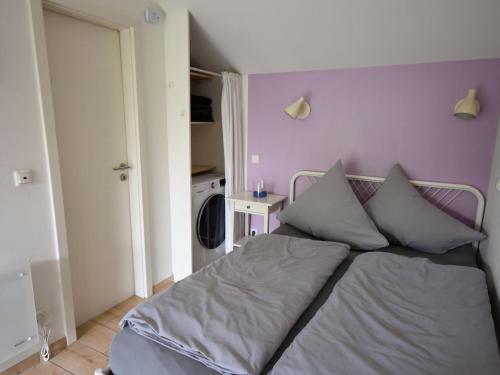 a bed in a bedroom with a purple wall at Cottage in Germany with Sun Terrace & BBQ in Berlingen