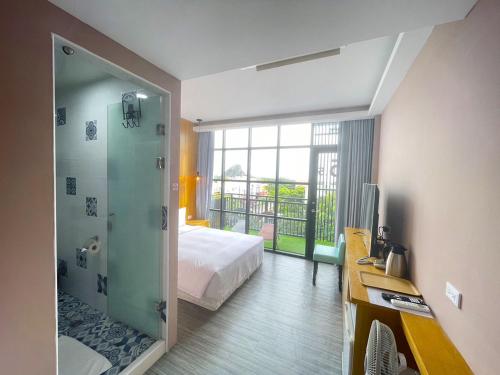 ein Hotelzimmer mit einem Bett und einer Glasdusche in der Unterkunft 35.5 Inn in Kenting