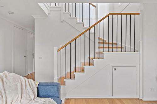 a white staircase in a living room with a blue chair at Paperbark Escape in Inverloch