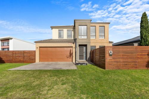 a house with a wooden fence and a garage at Paperbark Escape in Inverloch