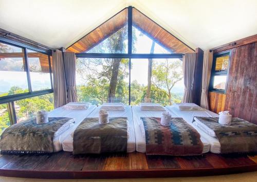 a large bed in a room with a large window at Baan Nhuer Mek บ้านเหนือเมฆ Coffee and Desk on the Cloud in Ban Pang Klang
