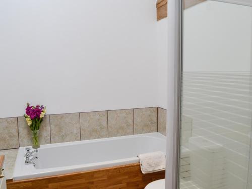 a bathroom with a shower and a bath tub with a vase of flowers at Midday in Silloth