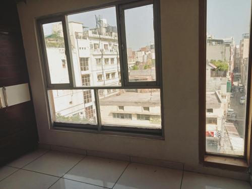 a room with three windows and a view of a city at Hotel Robin Inn in Amritsar