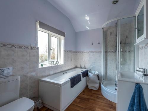 a bathroom with a tub and a toilet and a sink at Old Alton Hall Farmhouse in Tattingstone