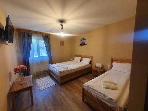 1 dormitorio con 2 camas y una mesa con flores en Pensiunea transilvania, en Covasna