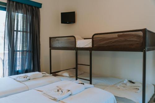 a room with three bunk beds and a television at Karavostasi Beach Hotel in Perdika