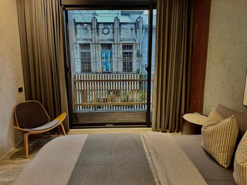 1 dormitorio con ventana grande con vistas a un edificio en HERE宅這兒私宅-屏市宅 en Pingtung City