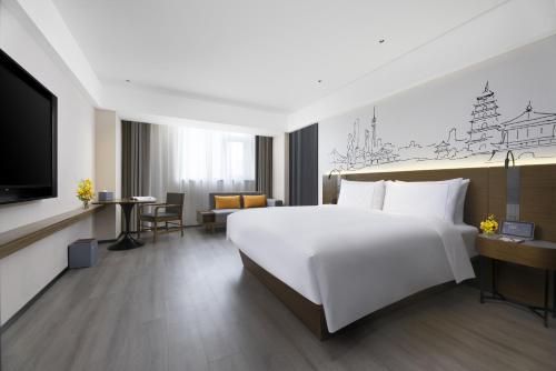 a hotel room with a large bed and a tv at UrCove by Hyatt Xi'an Hi-Tec in Xi'an