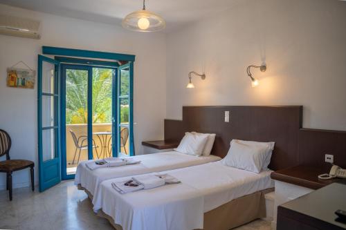 a hotel room with two beds and a balcony at Karavostasi Beach Hotel in Perdika