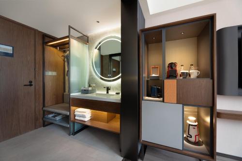 a bathroom with a sink and a mirror at UrCove by Hyatt Xi'an Hi-Tec in Xi'an