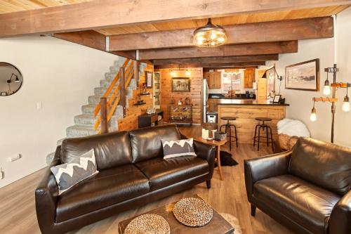 a living room with leather furniture and a staircase at Sugar in the Raw Cabin - Hot Tub in Sugarloaf