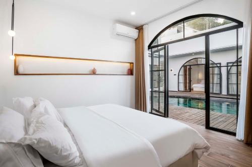- une chambre avec un lit blanc et une piscine dans l'établissement Casa Copper by Alfred in Bali, à Canggu
