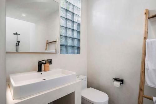 La salle de bains blanche est pourvue d'un lavabo et de toilettes. dans l'établissement Casa Copper by Alfred in Bali, à Canggu