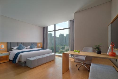 a hotel room with a bed and a desk and a desk at Pagoda Hotel Hangzhou Binjiang in Hangzhou