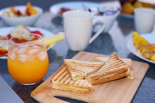 a wooden cutting board with toast and a glass of orange juice at Kiriakos Apartment in Kalamata