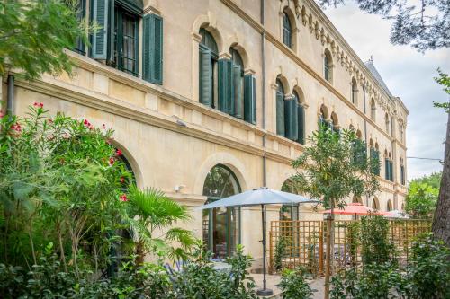 a building with an umbrella in front of it at 5 Family Apartments with Pool & Large Garden in Historic Pézenas Convent in Pézenas