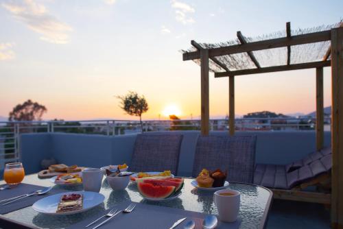 un tavolo con cibo in cima a un balcone con vista sul tramonto di Kiriakos Apartment a Kalamáta