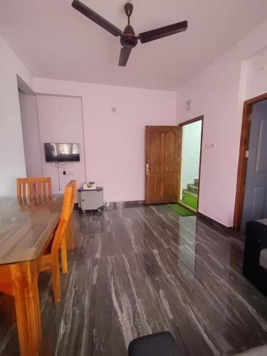 a living room with a wooden table and a ceiling fan at CITY APARTMENTS in Guruvāyūr
