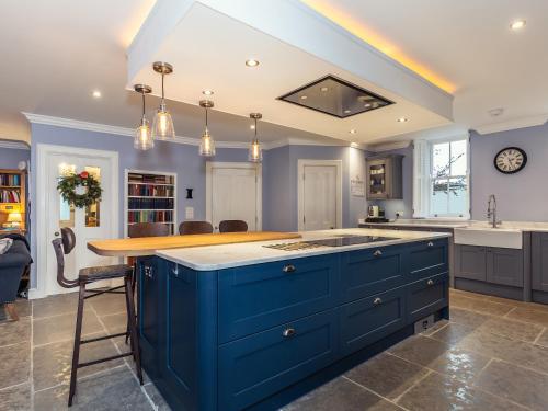 a kitchen with blue cabinets and a kitchen island at Vallis Oak Villa in Frome