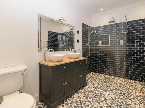 a bathroom with a sink and a toilet and a mirror at Vallis Oak Villa in Frome