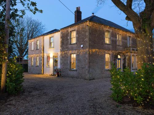an old brick house with christmas lights on it at Vallis Oak Villa in Frome