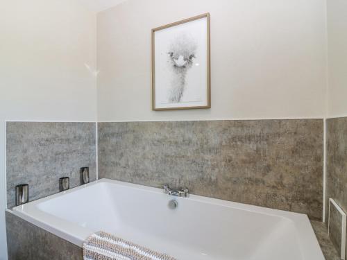 uma banheira na casa de banho com uma fotografia na parede em Stable Cottage em Inverurie