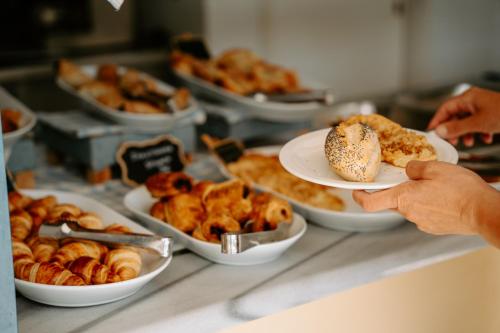 a person holding a plate of pastries on a counter at Karavostasi Beach Hotel in Perdika