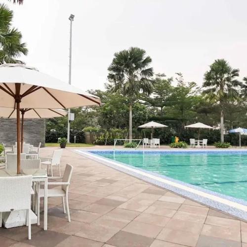 a swimming pool with tables and chairs and an umbrella at Salifa Rooms in Teko