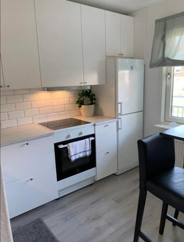 a kitchen with white cabinets and a stove and refrigerator at Glöm dina bekymmer i denna rymliga lägenhet in Trollhättan