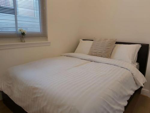 1 cama blanca en un dormitorio con ventana en Flat 7 - Newly Renovated en Portsmouth