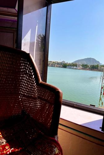 a chair in front of a window with a view of the water at Hotel Kota kunj Heritage in Pushkar