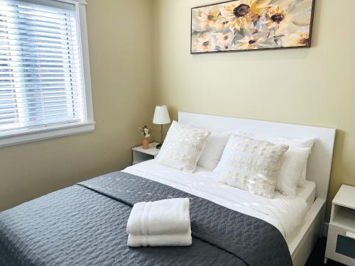 a bedroom with a white bed with pillows and a window at Jennifer's House in Vancouver