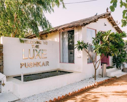 Ein weißes Haus mit einem Schild, auf dem steht: Willkommen in der lebenden Puschkarma. in der Unterkunft The Luxe Pushkar By Namli Hotels in Pushkar