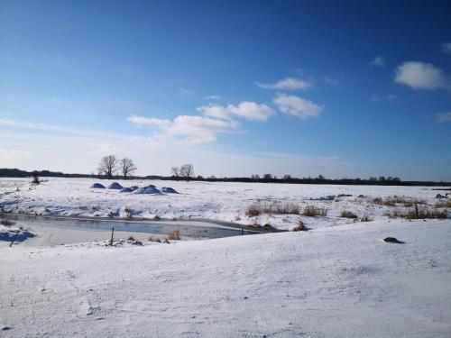 a snow covered field with a river in the middle at Chatka skrzatka in Kruki