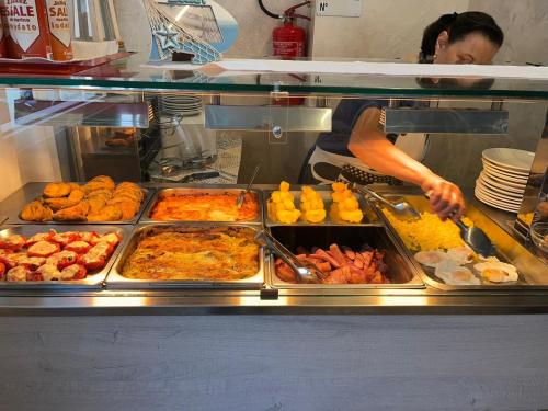 una mujer está preparando comida en un buffet en Hotel Monica, en Rímini