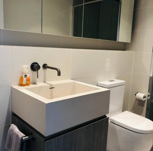 a white bathroom with a sink and a toilet at Sky Apartment - Realm Adelaide in Adelaide